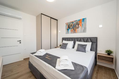 a bedroom with a large bed with two towels on it at Poolside Hideout Apartments in Novalja