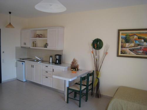 a kitchen with white cabinets and a table and a counter at Popi Studios in Arkasa