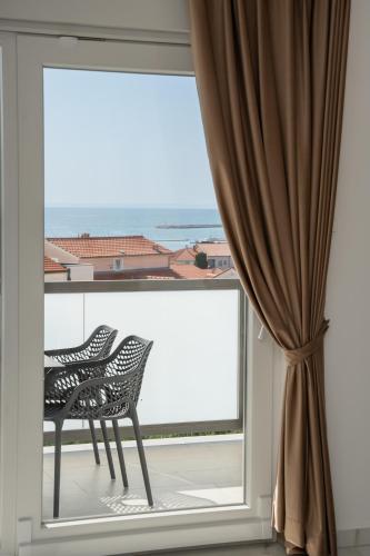 two chairs sitting on a balcony with a large window at Poolside Hideout Apartments in Novalja