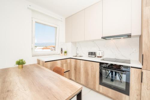 a kitchen with white cabinets and a wooden table at Poolside Hideout Apartments in Novalja