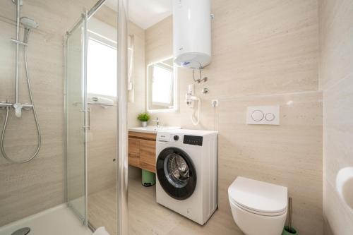 a bathroom with a washing machine and a toilet at Poolside Hideout Apartments in Novalja