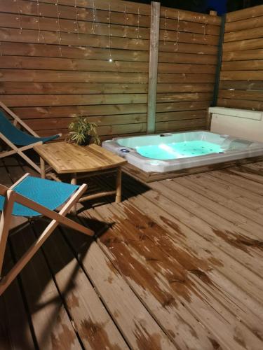 a jacuzzi tub on a deck with a chair at Le Chalet Champenois - Jacuzzi - Terrasse - Calme - Ciné Netflix in Troyes