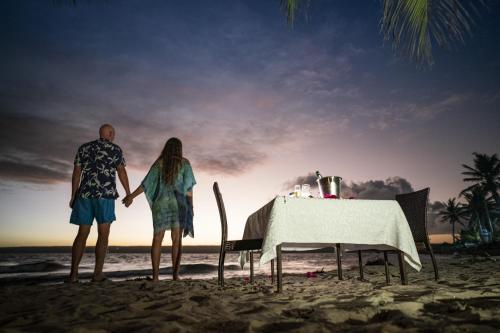 a man and woman standing on the beach with a table at Castelo Beach Resort in Inhambane