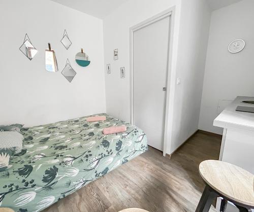 - une petite chambre avec un lit et une couverture verte dans l'établissement Studio à Montluçon, à Montluçon