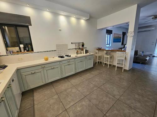 a large kitchen with white cabinets and a table at קסם כפרי in Maslul