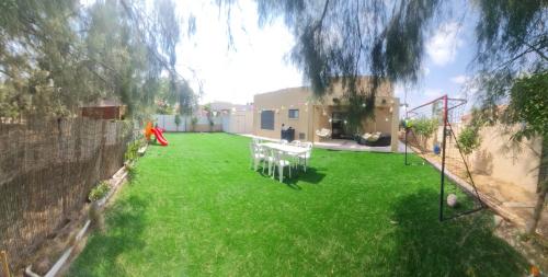 a lawn with tables and chairs in a yard at קסם כפרי in Maslul