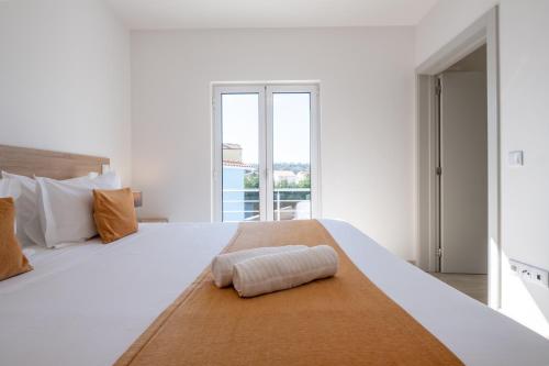 a white bedroom with a large bed with a large window at Villa Montês - Exclusive Apartments & Prime Location in Coja