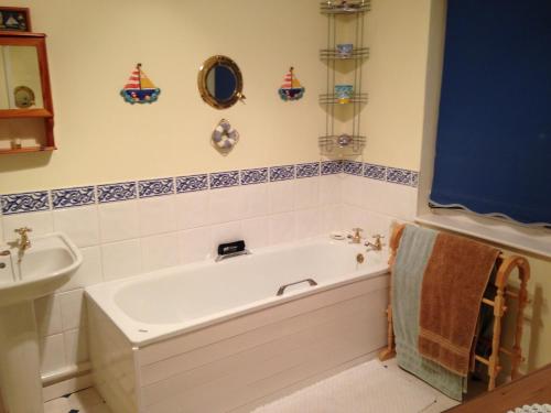 a bathroom with a bath tub and a sink at Traditional 2 Bedroom Thatched Cottage in East Budleigh