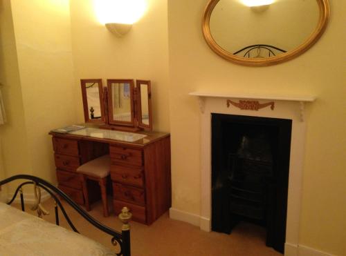 a bedroom with a dresser and a mirror and a fireplace at Traditional 2 Bedroom Thatched Cottage in East Budleigh