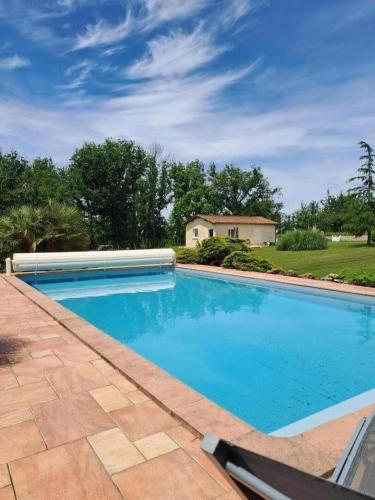 une grande piscine bleue avec une maison en arrière-plan dans l'établissement La belle etoile, à Saint-Aulaye