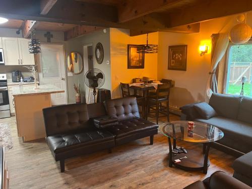 Una sala de estar con un sofá de cuero y una mesa. en The Red Door Residence, en North Pole