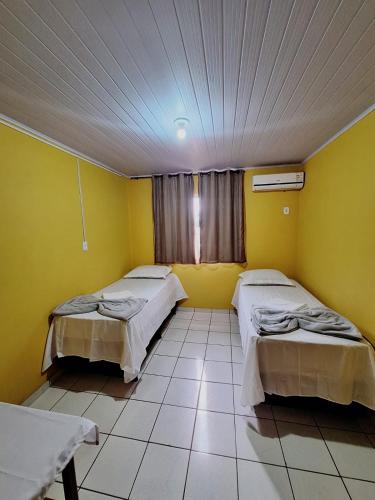 two beds in a room with yellow walls at Pousada Alma Jalapoeira - Mateiros in Mateiros