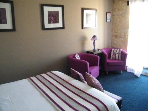 a hotel room with a bed and two chairs at Logis-Hôtel Côté-Rivage in Badefols-sur-Dordogne