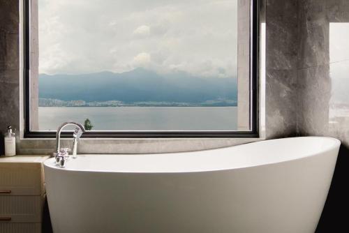 a bath tub in a bathroom with a window at 慢境Slow Land半山海景花园酒店 in Dali