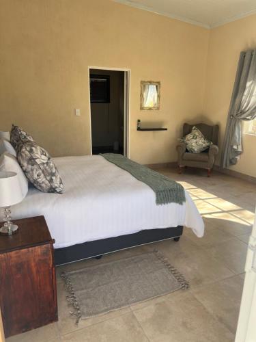 a bedroom with a large bed and a chair at Kaoko Bush Lodge in Kamanjab