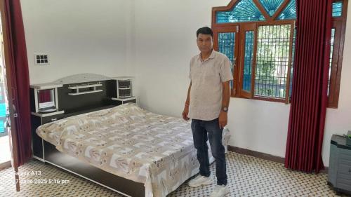 a man standing next to a bed in a room at Shri Satyanarayan ji homestay in Ayodhya