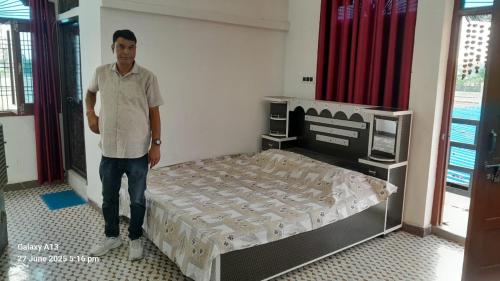 a man standing next to a bed in a room at Shri Satyanarayan ji homestay in Ayodhya
