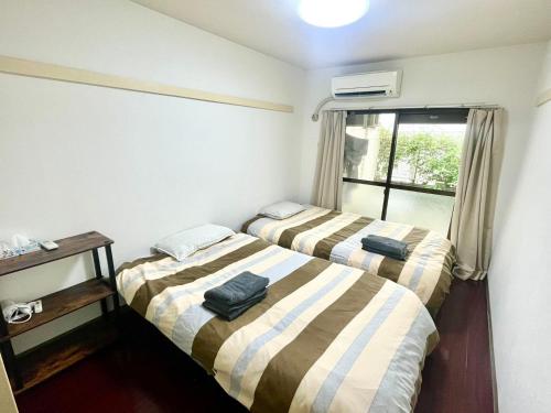 Dos camas en una habitación pequeña con ventana. en shibuya Honmachi Studio, en Tokio