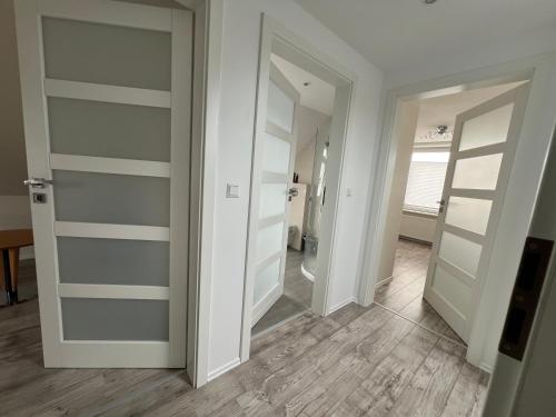 a hallway with white doors and wooden floors at Apartment am Eichhof in Seevetal