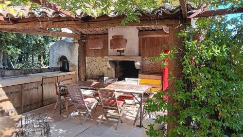 un patio con mesa, sillas y horno en Le mas des louquiers, en Mons