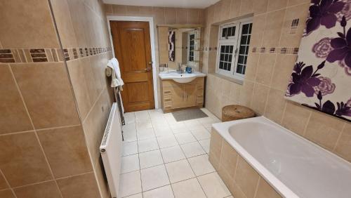 a bathroom with a tub and a sink at SnoozeDen Westmead - Windsor Castle & Legoland in Windsor