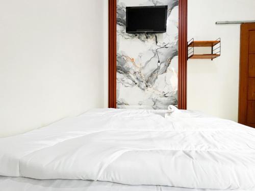 a bedroom with a white bed and a tv on a wall at Labella Homestay 2 Syariah RedPartner near 0 KM Dieng in Dieng