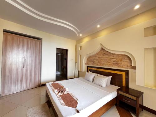Un dormitorio con una cama grande y una pared de ladrillo. en Usiku Mwema Beachfront Apartments, en Mombasa