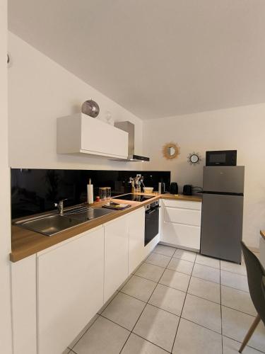 a white kitchen with a sink and a refrigerator at L'Echappée Urbaine - 2 personne proche - centre ville in Saint-Brieuc