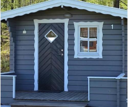 a blue house with a door and a window at Halens Camping och Stugby in Olofström