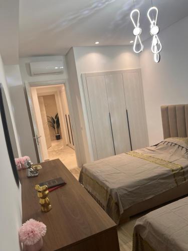 a bedroom with two beds and a table and a chandelier at Blue Bay Appart hôtel in Monastir