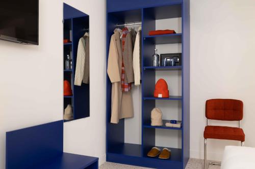 a blue book shelf with clothes and a chair at Seb & Co in Paris