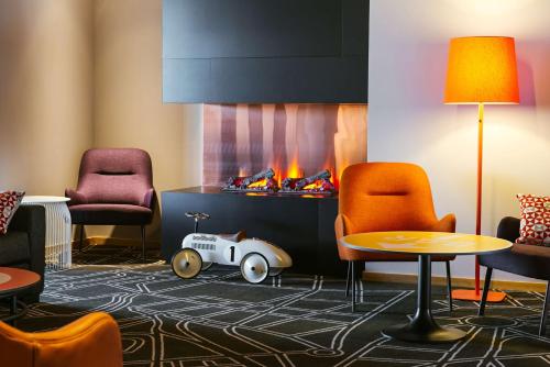 a living room with a fireplace and chairs and a table at Scandic Elmia in Jönköping