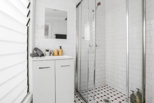 Un baño blanco con ducha y lavabo. en 2 Bedroom House Woolloomooloo, en Sídney