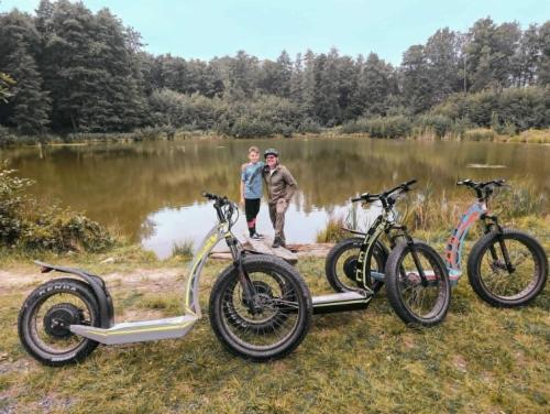 two people standing next to two bikes parked next to a lake at Kaczawska Chata z wypożyczalnią e-hulajnóg terenowych 