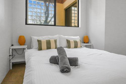 Un dormitorio con una cama blanca con dos ventanas. en 2 Bedroom House Woolloomooloo, en Sídney