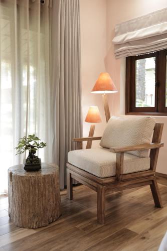 a room with a chair and a table with a lamp at Palm Garden Beach Resort & Spa in Hoi An