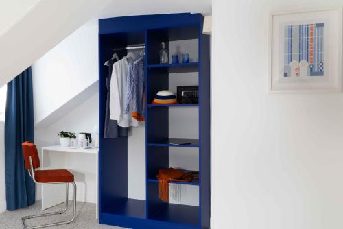 a blue book shelf in a room with a chair at Seb & Co in Paris