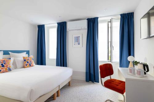a bedroom with blue curtains and a bed and a chair at Seb & Co in Paris
