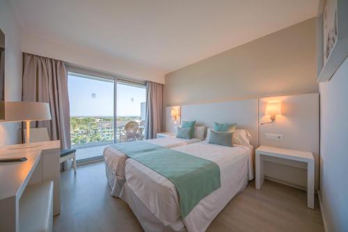 a hotel room with a bed and a large window at Playa Esperanza Resort Affiliated by Meliá in Playa de Muro