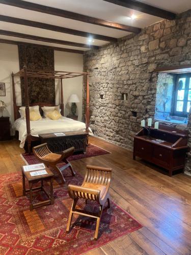 une chambre avec un lit et un mur en pierre dans l'établissement Le Château de Sorgues, à Cornus