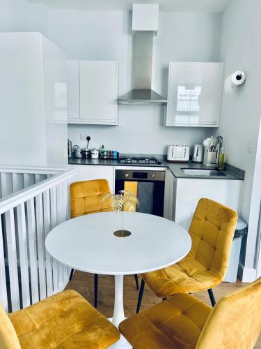 a white kitchen with a white table and chairs at Folkestone Harbour - 3 Bed sleeps 7 Ground Floor in Dover