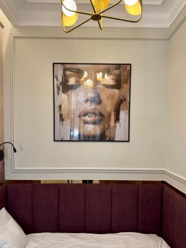a painting of a woman on a wall above a bed at ROOSEVELTA RESIDENCE Apartments - przy OFF Piotrkowska in Łódź