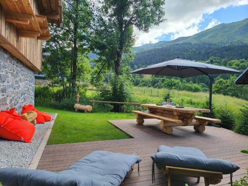 une terrasse avec un parasol, une table et des bancs dans l'établissement Le Chalet des Amis - Meribel - piscine, ciné, salle de jeux, à Méribel