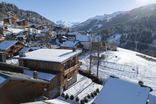 a town with snow covered roofs and buildings at Le Chalet des Amis - Meribel - piscine, ciné, salle de jeux in Méribel