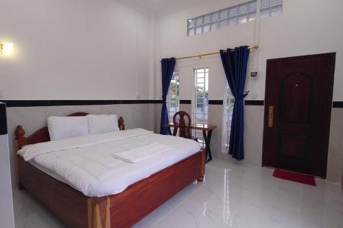 a bedroom with a bed and a table and a window at Phnom Sampov Homestay ផ្ទះលំហែភ្នំសំពៅ in Phumĭ Kdaông Khang Tbong