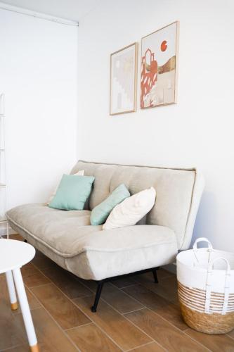 un canapé blanc avec des coussins dessus dans un salon dans l'établissement Studio tout confort - En plein centre de Lorient, à Lorient