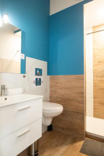 La salle de bains est pourvue de toilettes blanches et d'un mur bleu. dans l'établissement Hyper Centre Orléans : Magnifique appartement, à Orléans