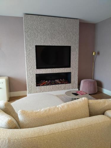 a living room with a couch and a fireplace at Van Der Valk Hotel Brugge Oostkamp in Oostkamp