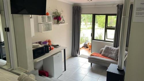 a small kitchen with a microwave and a chair at Footprints Self Catering Indoor Heated Pool and Fireplaces in Lanseria