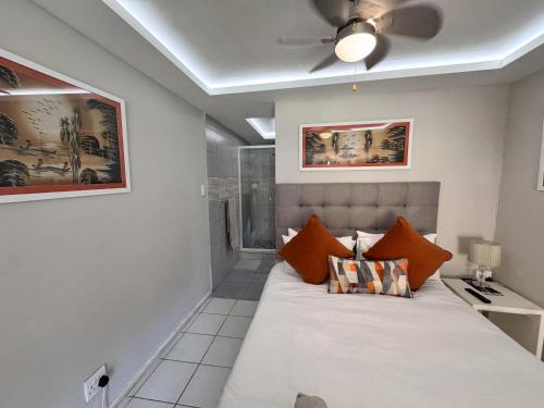 a bedroom with a large bed with a ceiling fan at Footprints Self Catering Indoor Heated Pool and Fireplaces in Lanseria